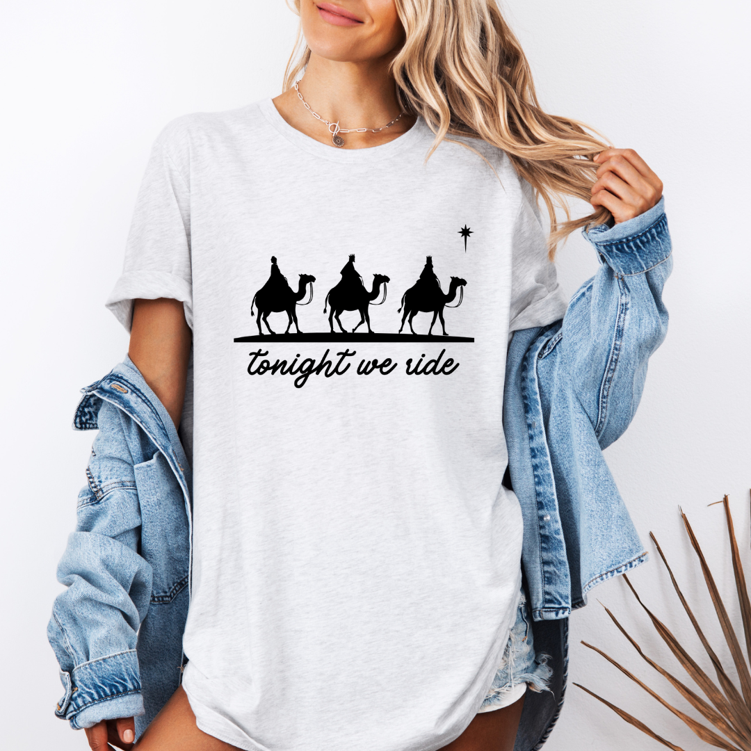 Ash white crewneck t-shirt that says, “tonight we ride” with an image of the three wisemen riding on camels towards the Christmas star.