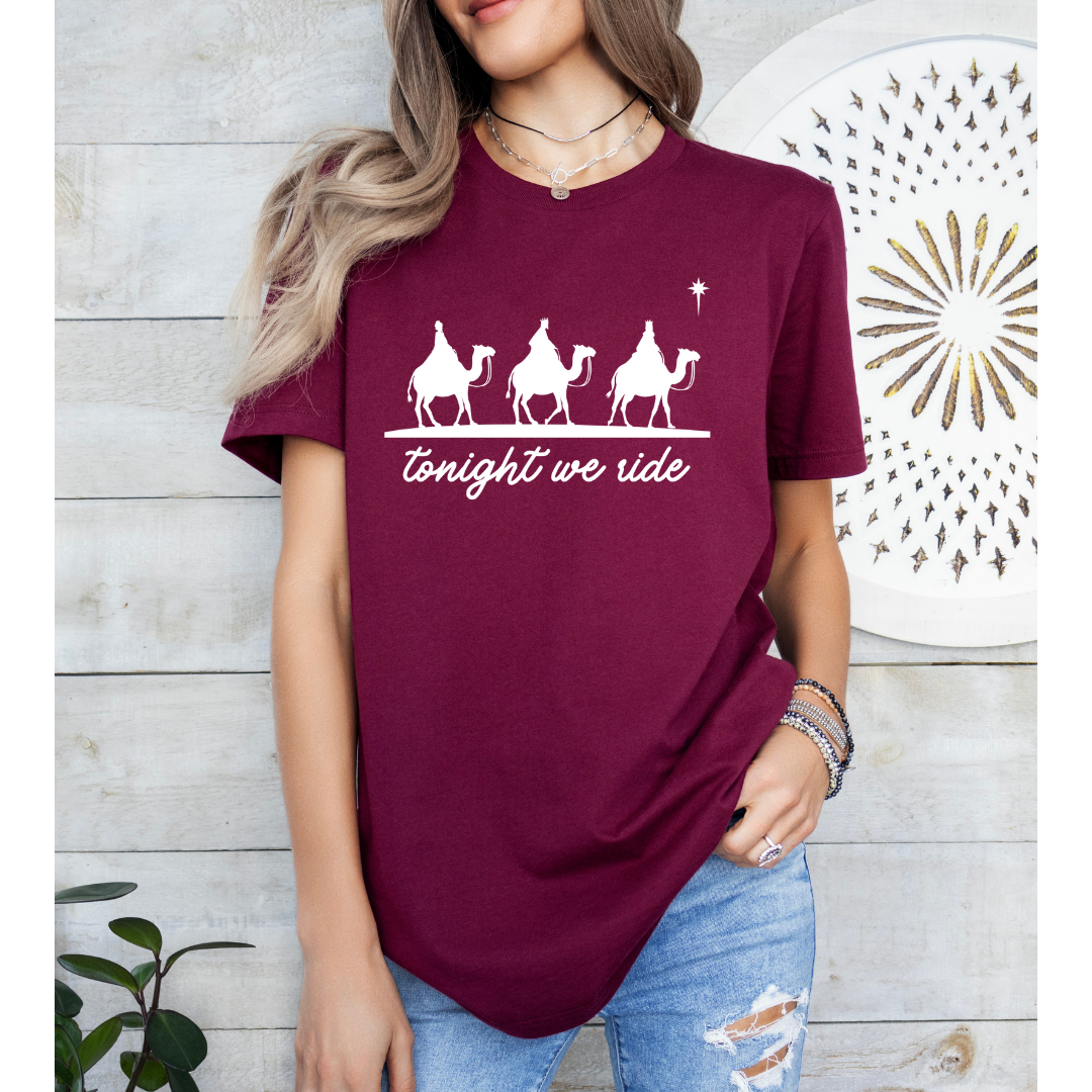 Maroon crewneck t-shirt that says, “tonight we ride” with an image of the three wisemen riding on camels towards the Christmas star.