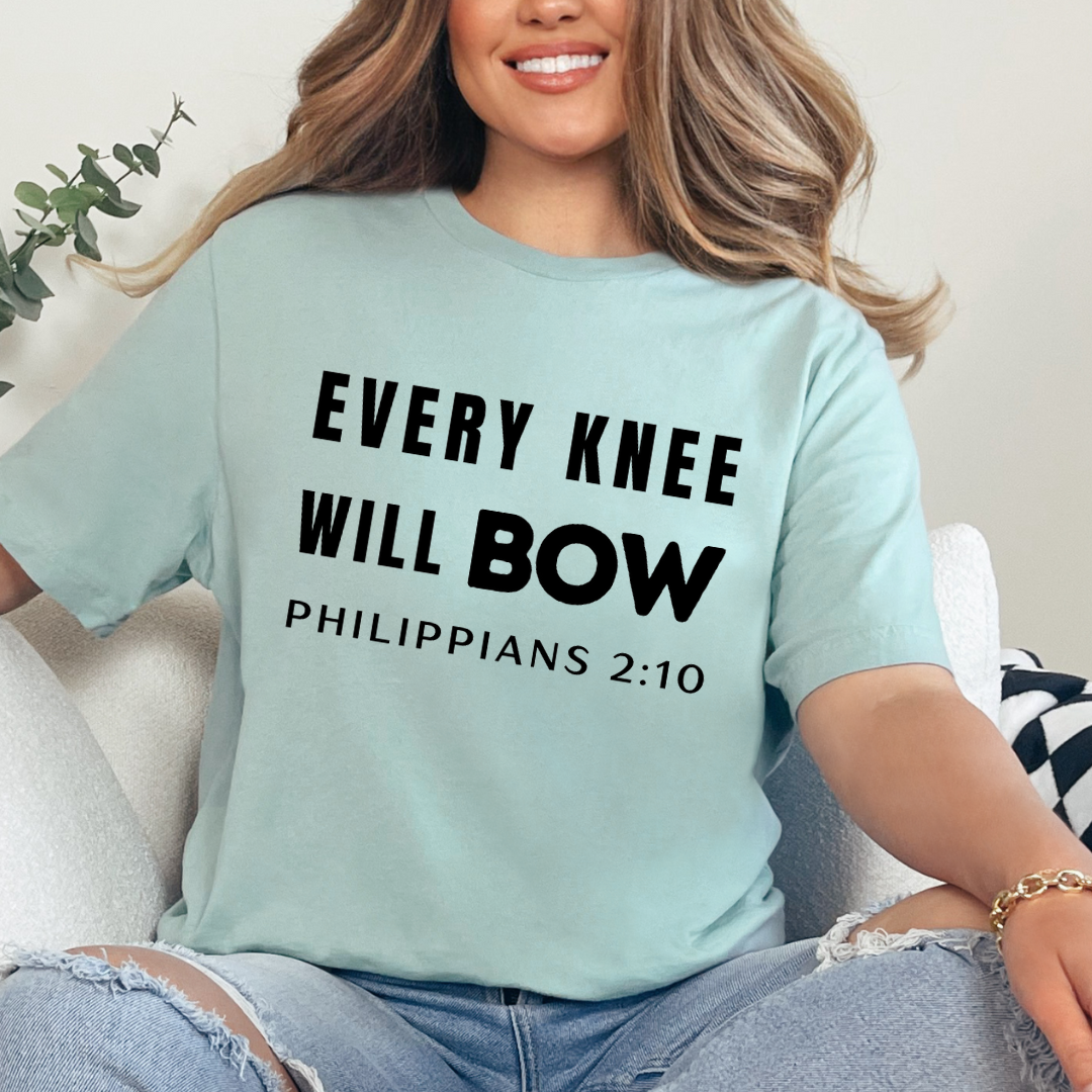 Dusty green crewneck t-shirt that says, “every knee will bow. Philippians 2:10.”