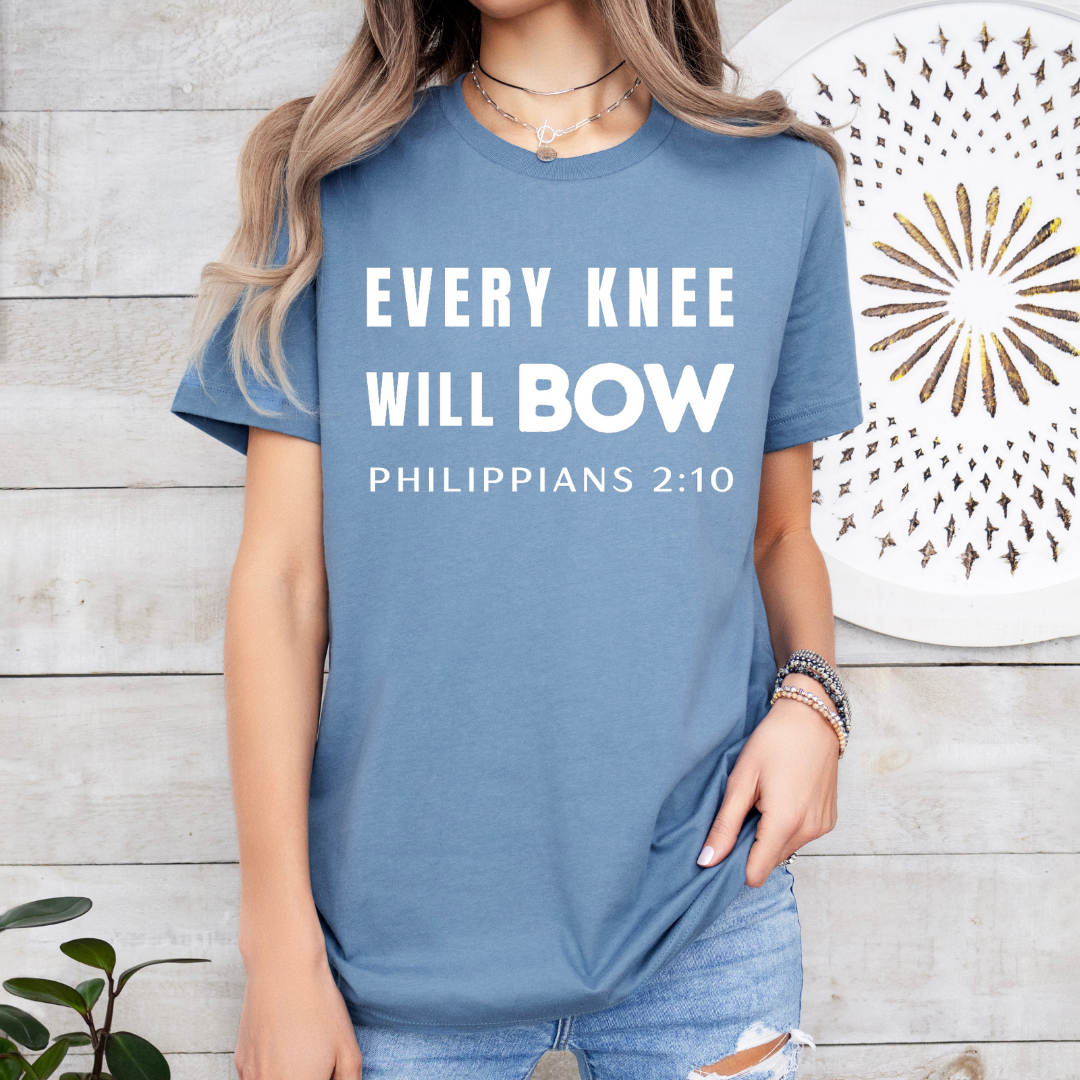 Steel blue crewneck t-shirt that says, “every knee will bow. Philippians 2:10.”