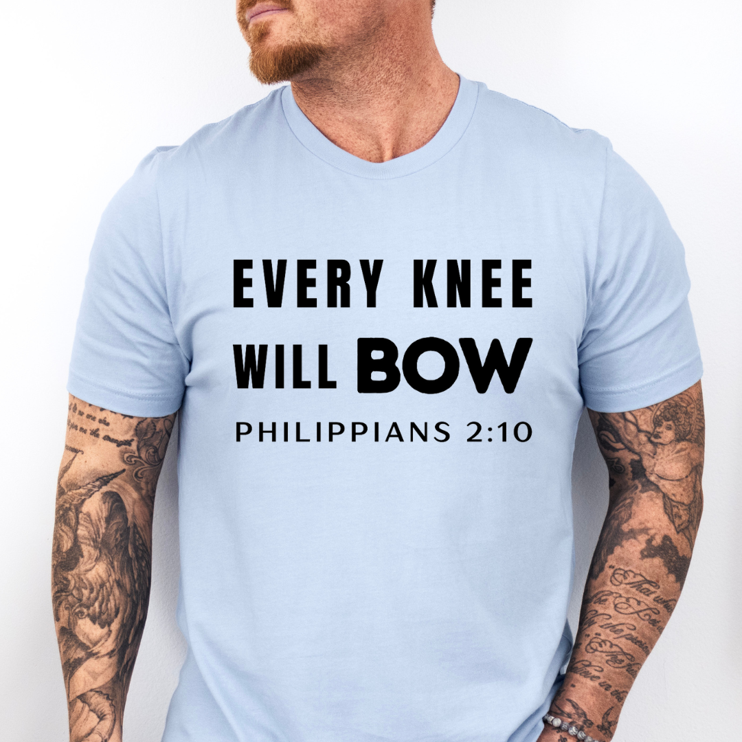 Baby blue crewneck t-shirt that says, “every knee will bow. Philippians 2:10.”