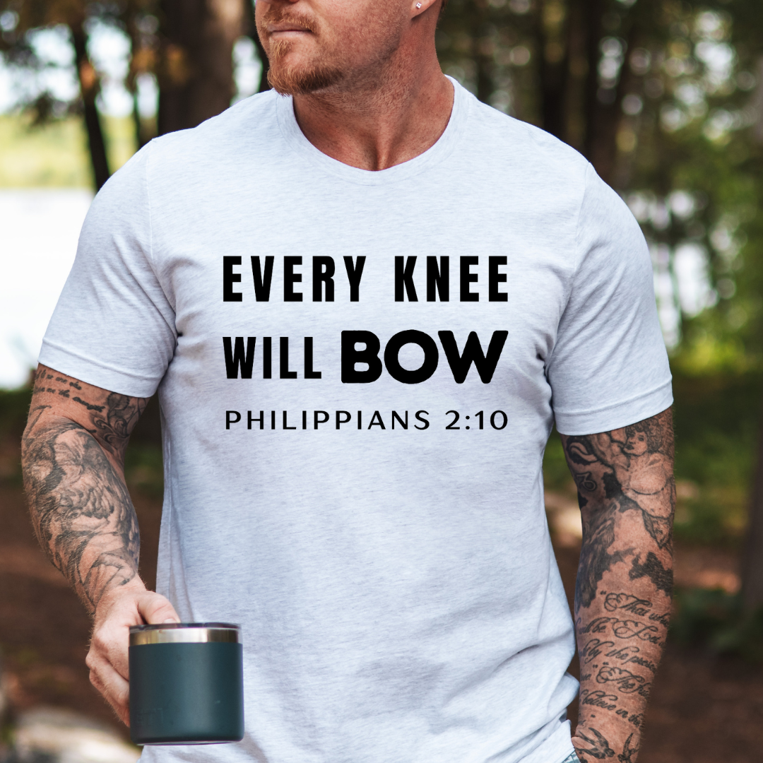 Ash white crewneck t-shirt that says, “every knee will bow. Philippians 2:10.”