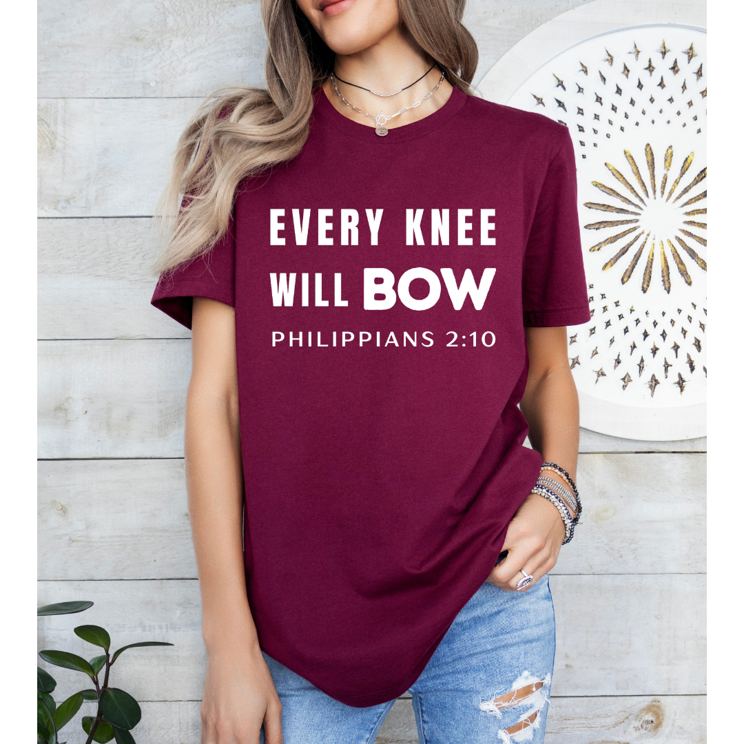 Maroon crewneck t-shirt that says, “every knee will bow. Philippians 2:10.”