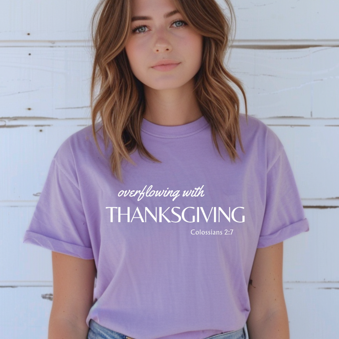 Lavender crewneck t-shirt that says, "overflowing with thanksgiving. Colossians 2:7." 